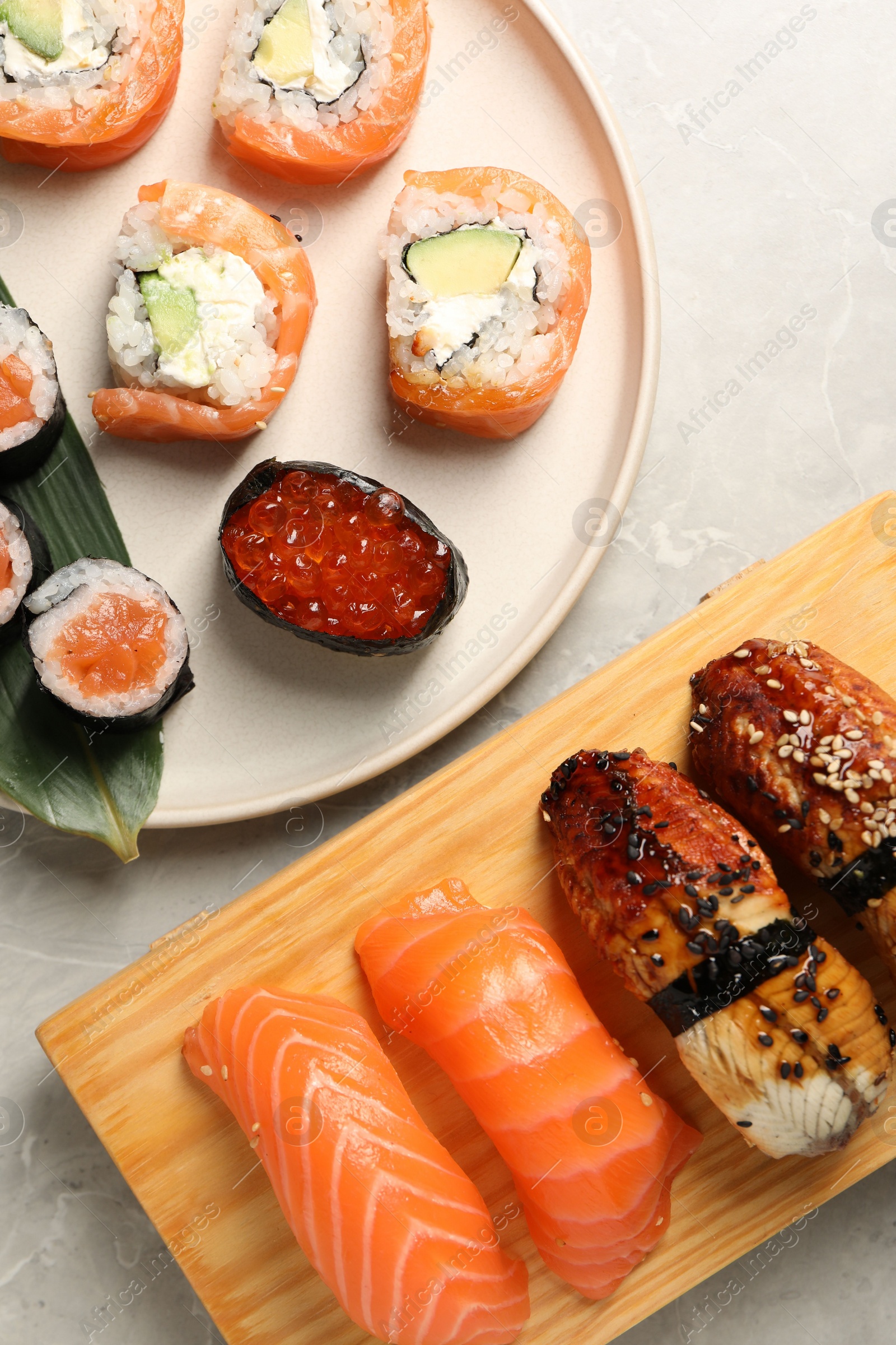 Photo of Delicious sushi rolls on light grey marble table, flat lay