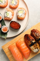 Delicious sushi rolls on light grey marble table, flat lay