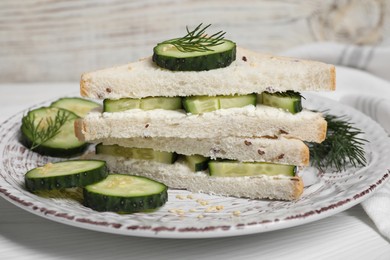 Tasty cucumber sandwiches with sesame seeds and dill on white wooden table, closeup