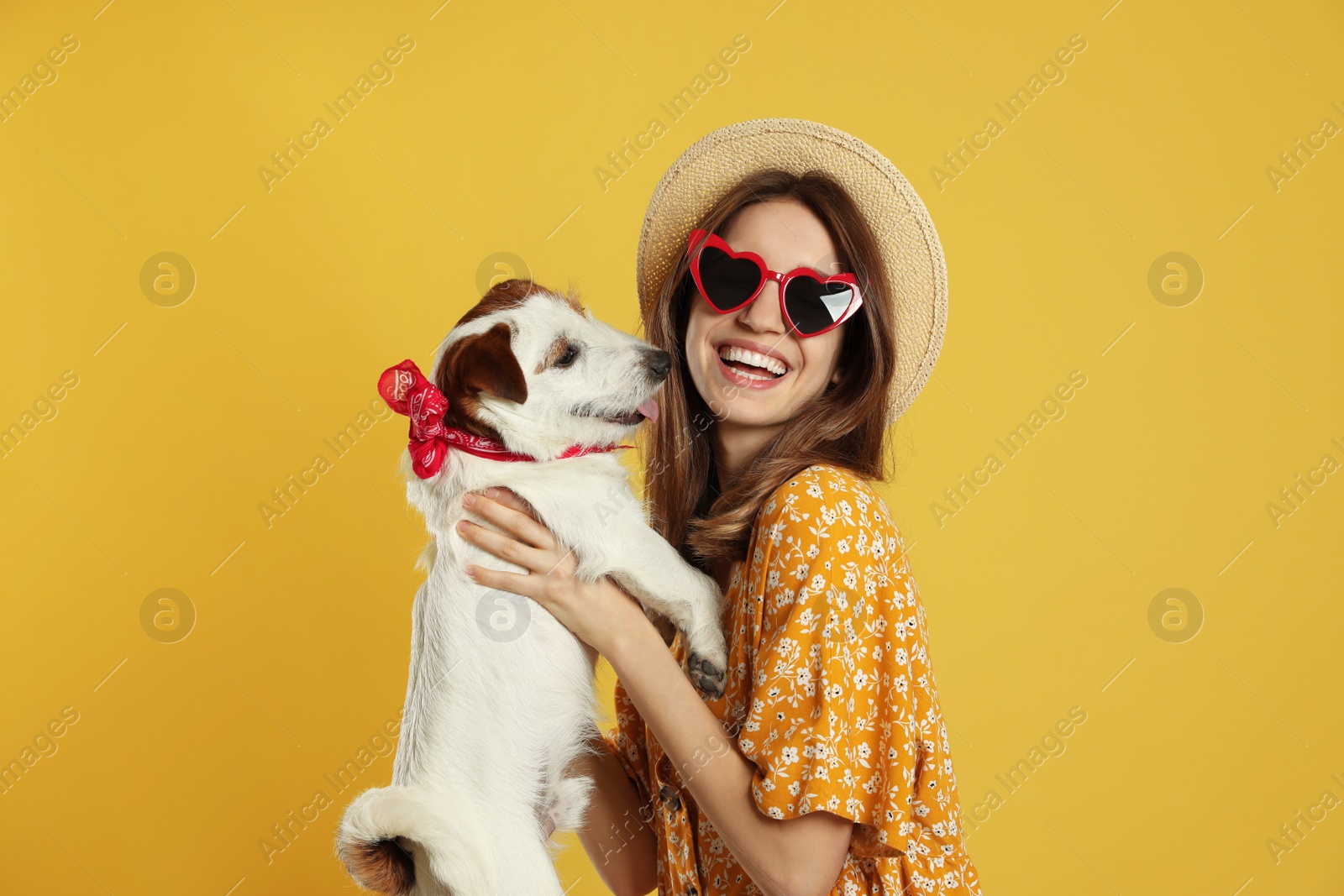 Photo of Young woman with her cute Jack Russell Terrier on yellow background. Lovely pet