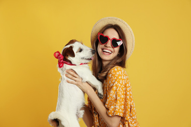 Young woman with her cute Jack Russell Terrier on yellow background. Lovely pet