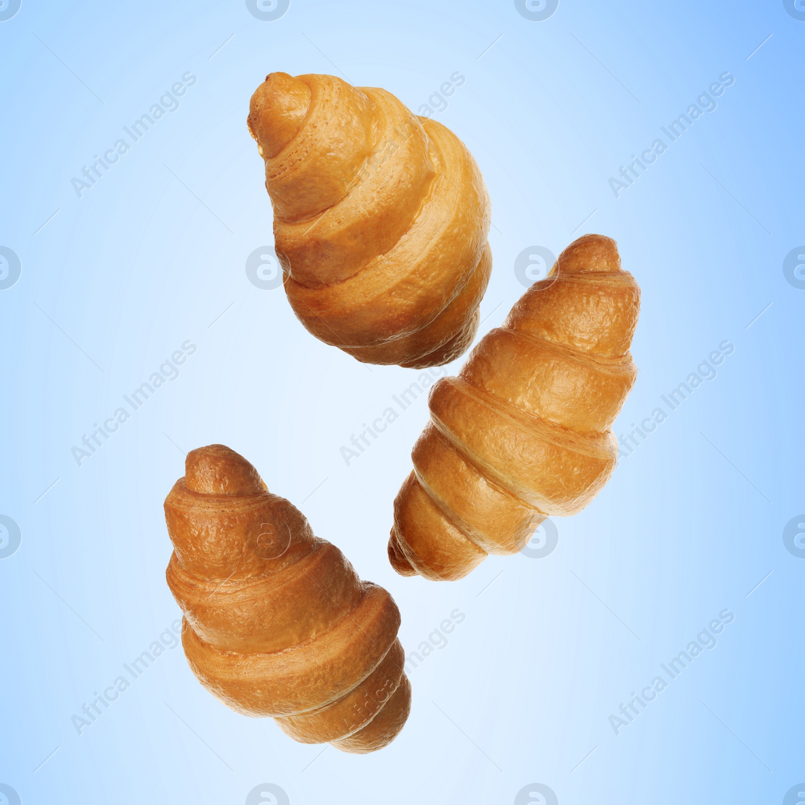 Image of Golden croissants falling on light blue gradient background