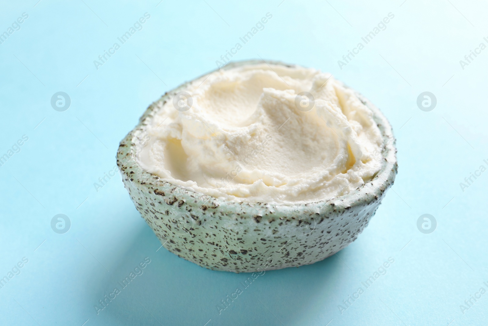 Photo of Bowl of tasty cream cheese on color background