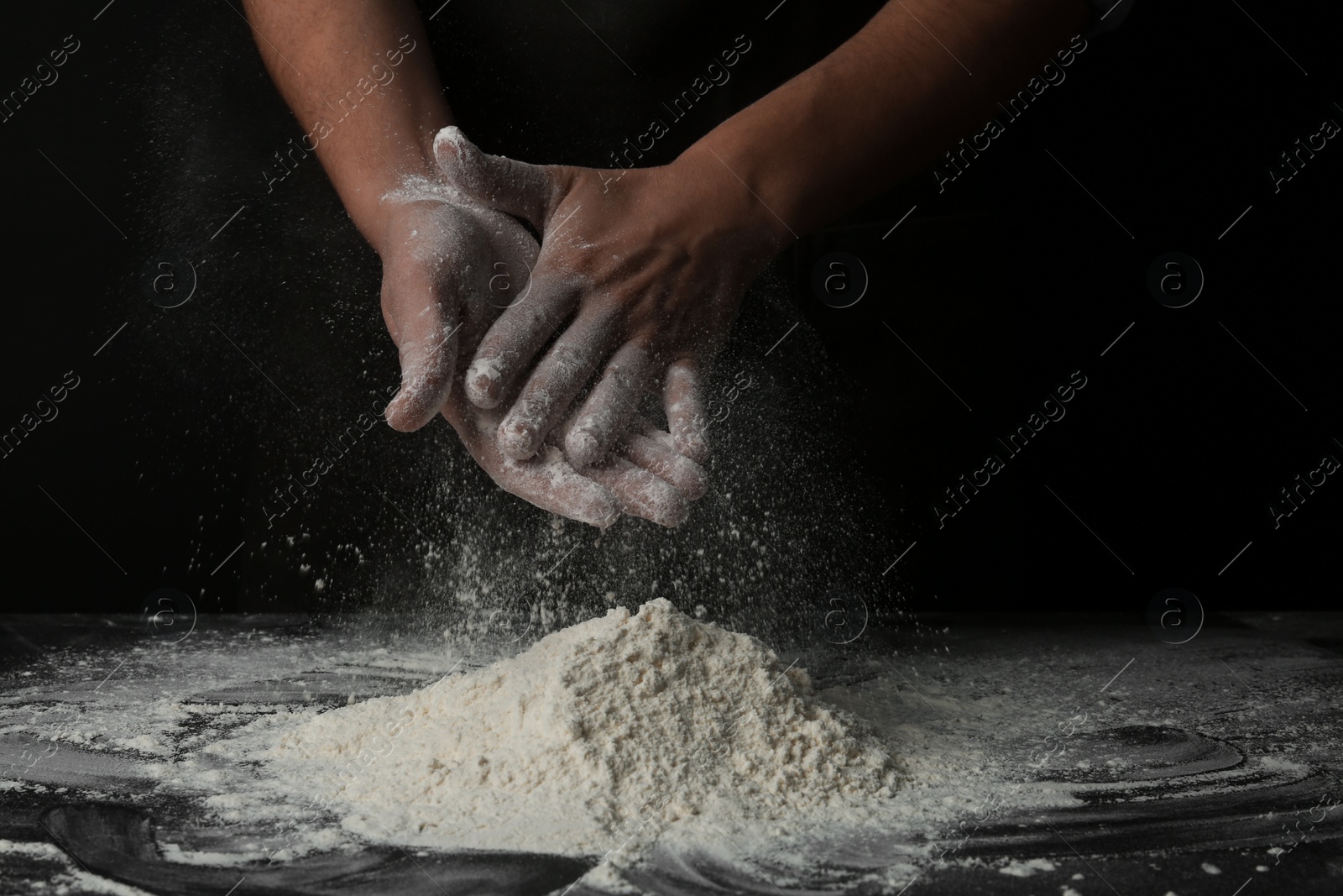 Photo of Baker with flour at dark table, closeup