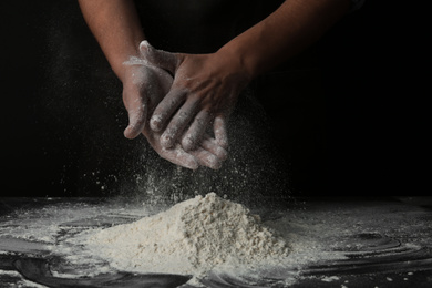 Baker with flour at dark table, closeup