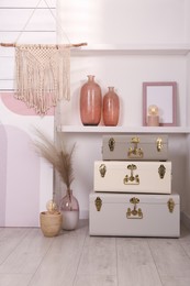 Photo of Stylish storage trunks and different decor elements near white wall indoors. Interior design