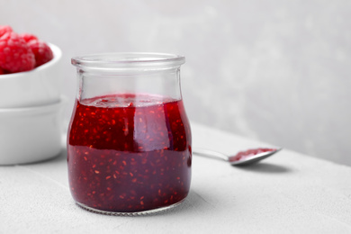 Delicious jam and fresh raspberries on light table. Space for text