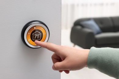 Image of Smart home system. Woman using thermostat indoors, closeup