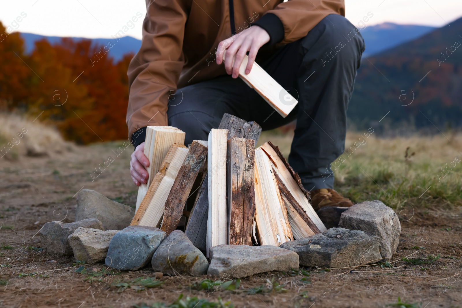 Photo of Traveler making bonfire with dry wood outdoors, closeup