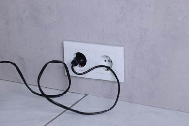 Power sockets and electric plug on grey wall