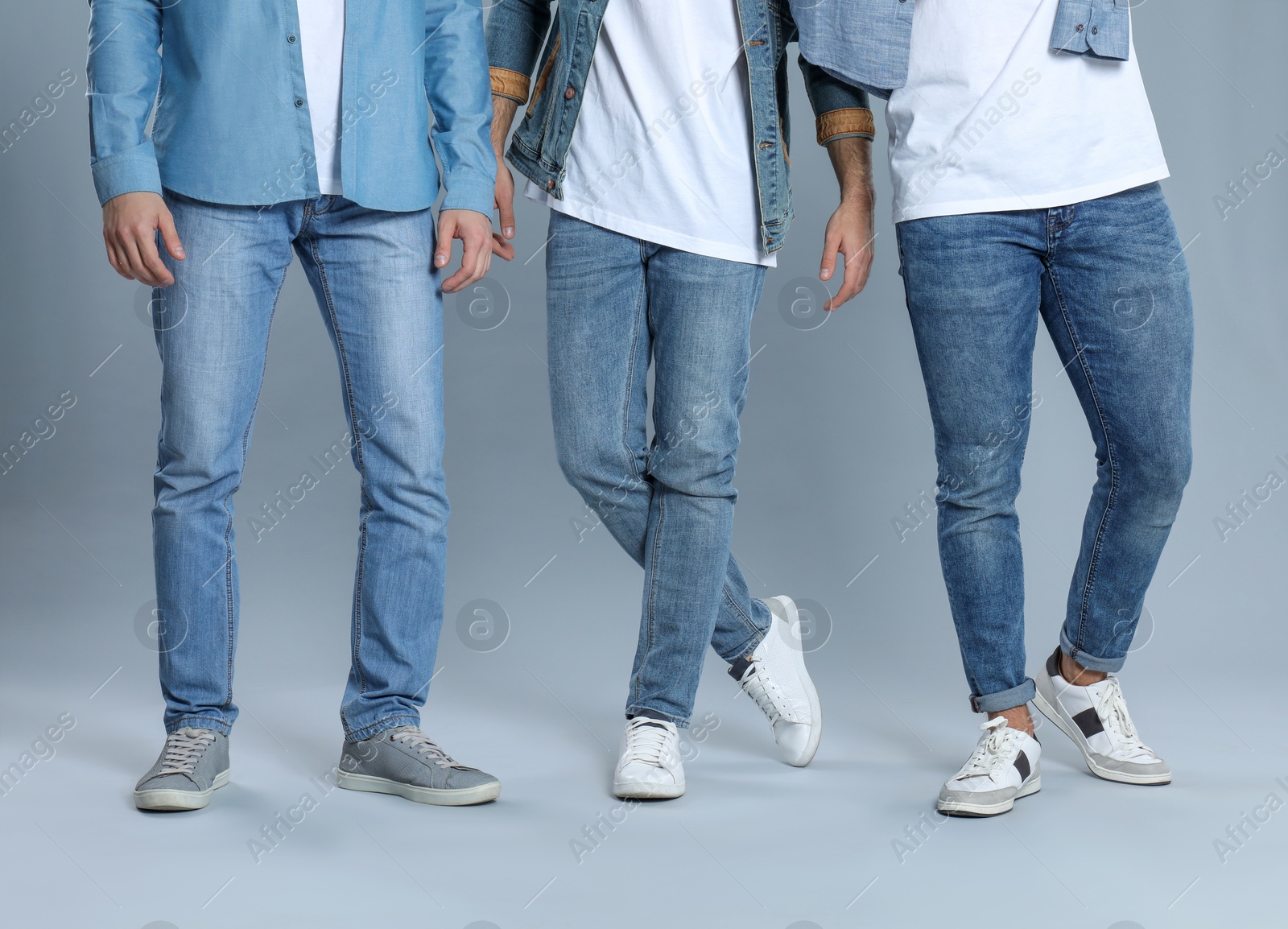 Photo of Group of young men in stylish jeans on grey background, closeup