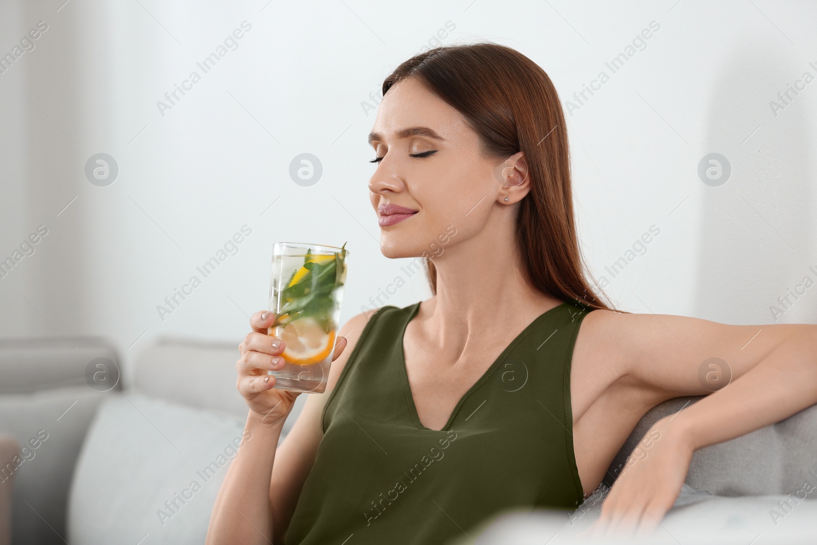 Photo of Young woman with lemonade at home. Refreshing drink