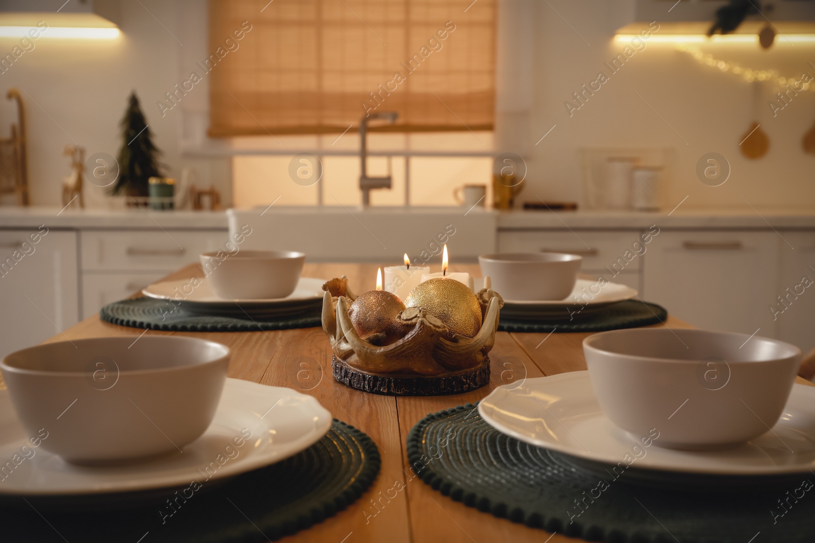 Photo of Table with dishware in beautiful kitchen decorated for Christmas, closeup