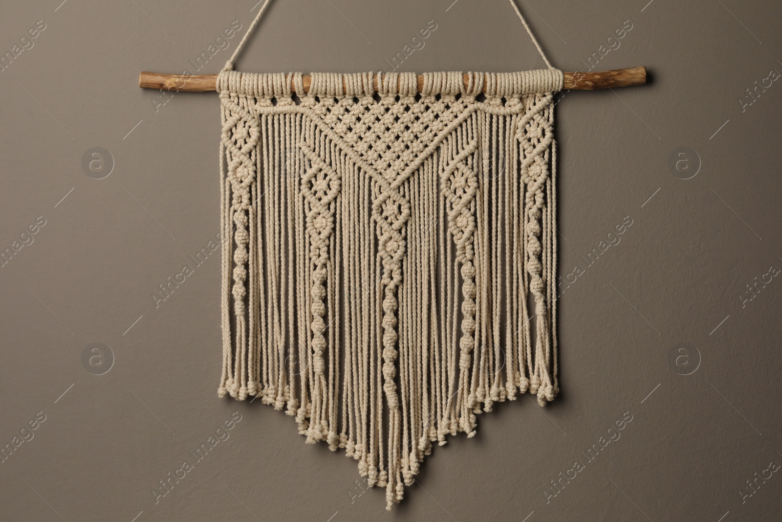 Photo of Beautiful macrame hanging on grey wall. Decorative element