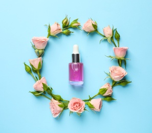Photo of Flat lay composition with fresh flowers and bottle of rose essential oil on color background