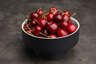Bowl with ripe sweet cherries on dark grey table