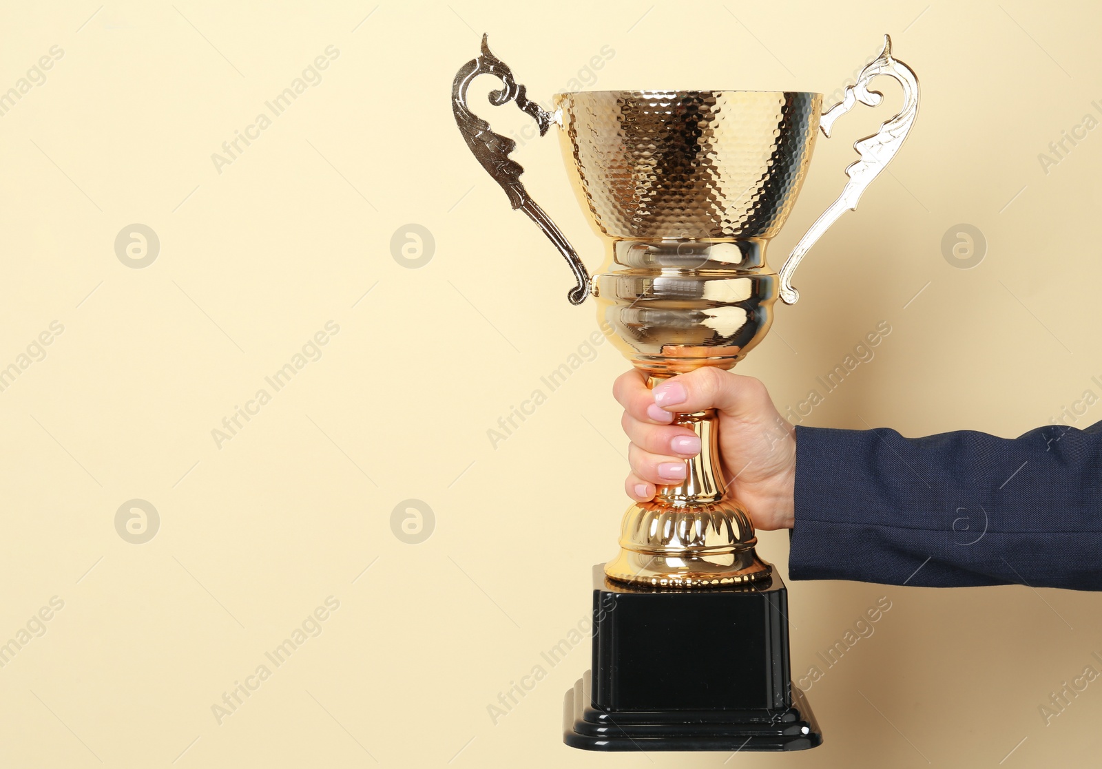 Photo of Woman holding golden trophy cup on color background, closeup. Space for text