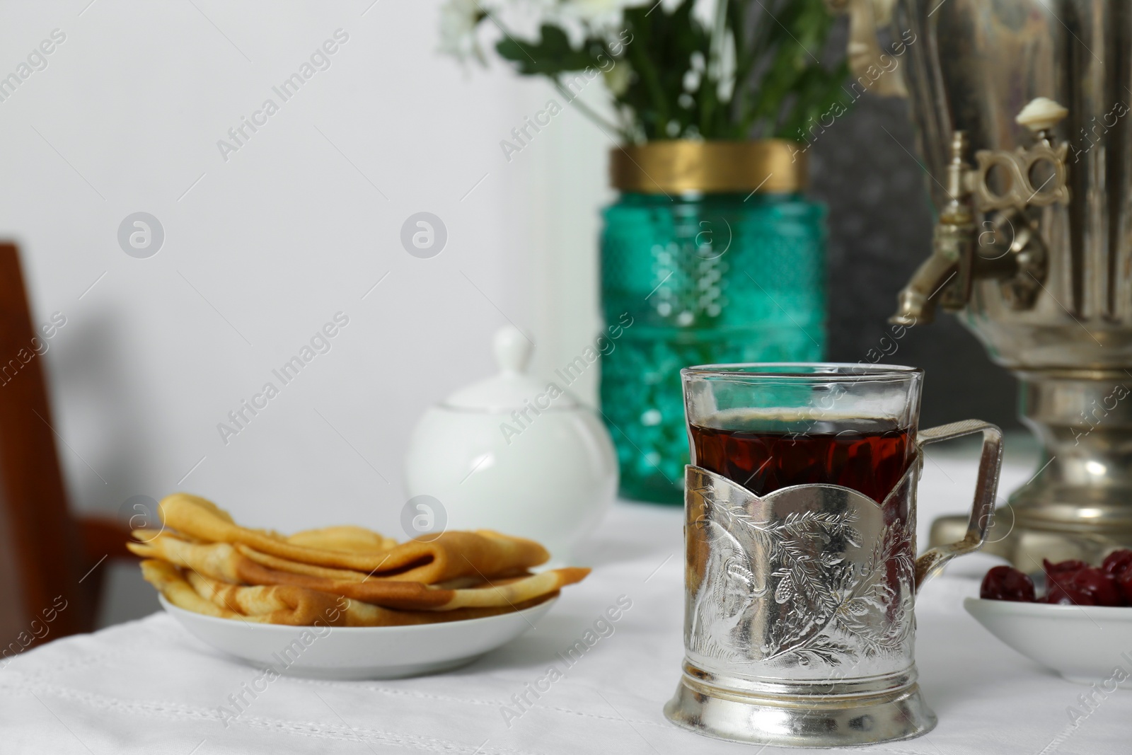 Photo of Traditional Russian samovar, aromatic tea and treats on table indoors