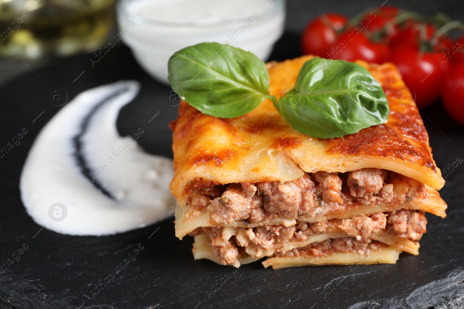 Photo of Delicious cooked lasagna served on slate plate, closeup