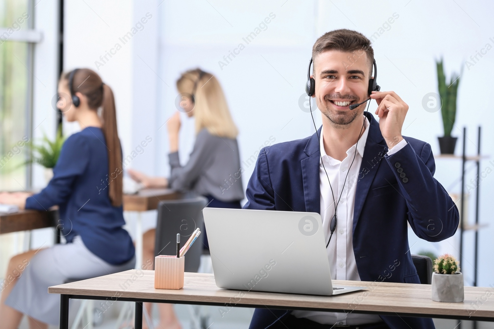 Photo of Male receptionist with headset at desk in office