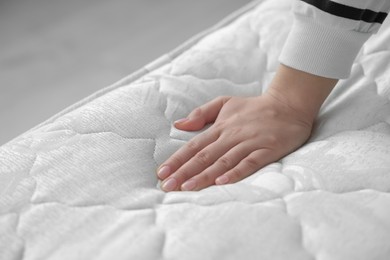 Photo of Woman touching soft white mattress indoors, closeup