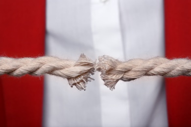Photo of Woman pulling frayed rope with tension, closeup