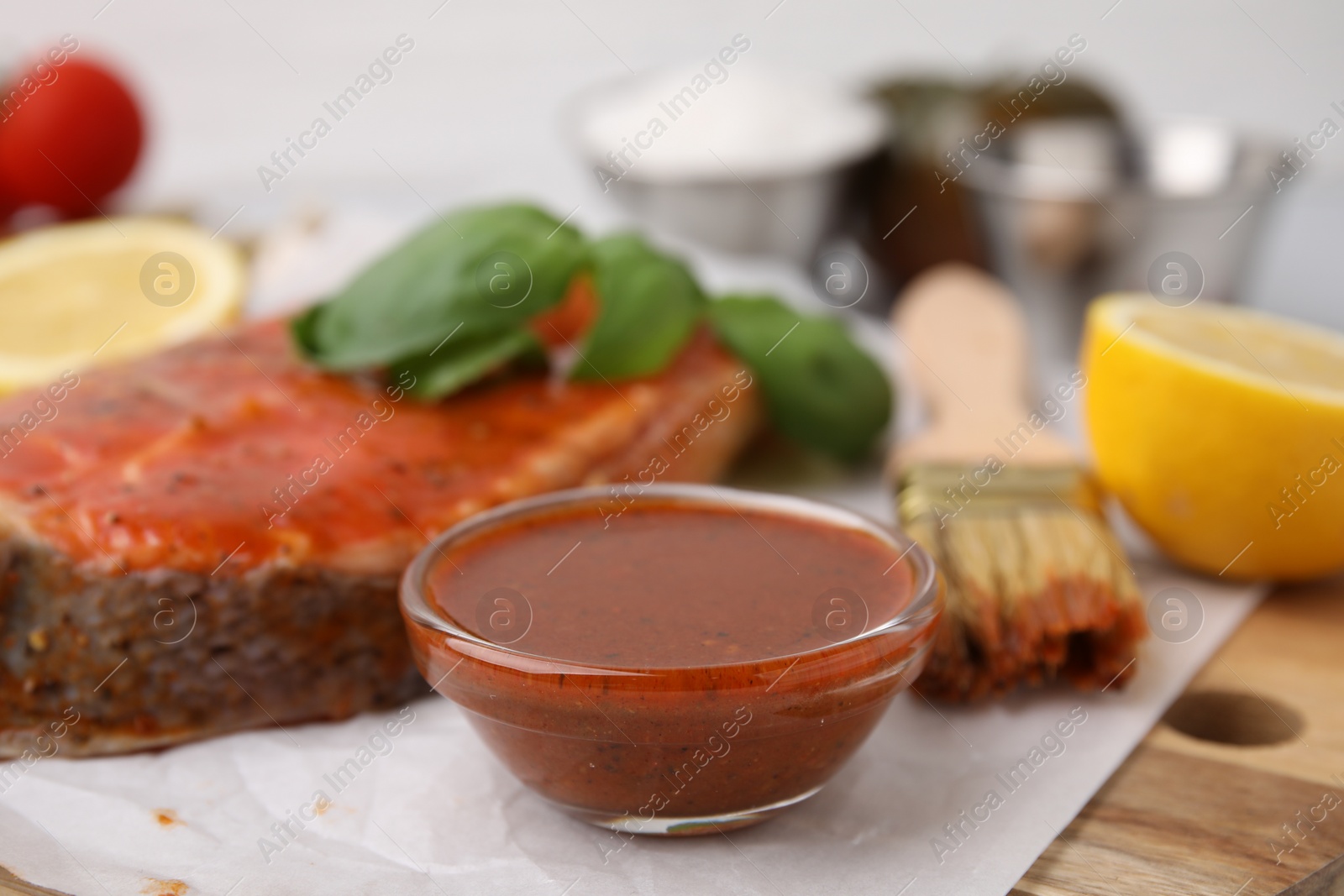 Photo of Fresh marinade, fish, lemon, brush and basil on table, closeup