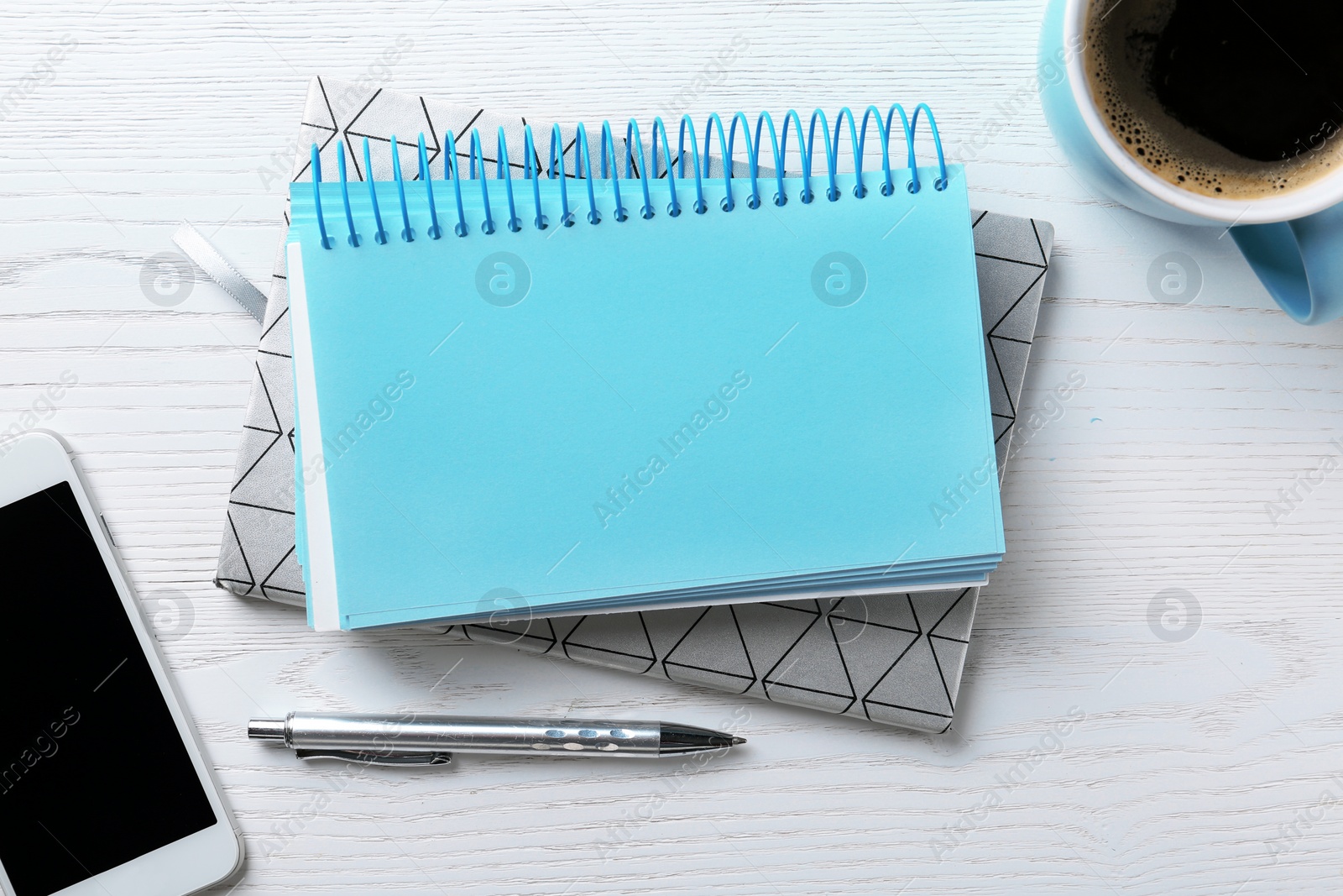 Photo of Flat lay composition with stationery, cup of coffee and smartphone on white wooden background. Space for text