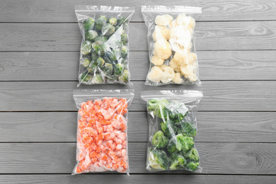 Photo of Different frozen vegetables on light grey wooden table, flat lay