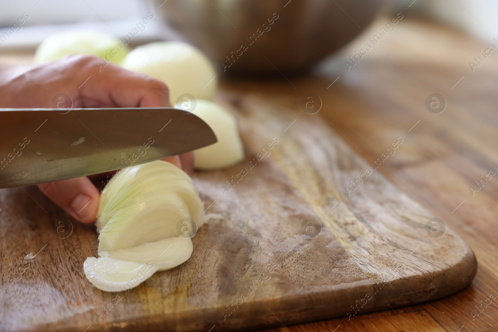 Photo of Woman cutting fresh ripe onion on wooden board, closeup. Space for text