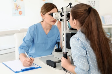 Photo of Ophthalmologist examining little girl in clinic