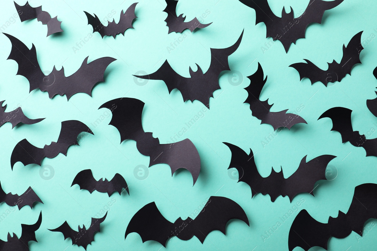 Photo of Many black paper bats on light blue background, flat lay. Halloween decor