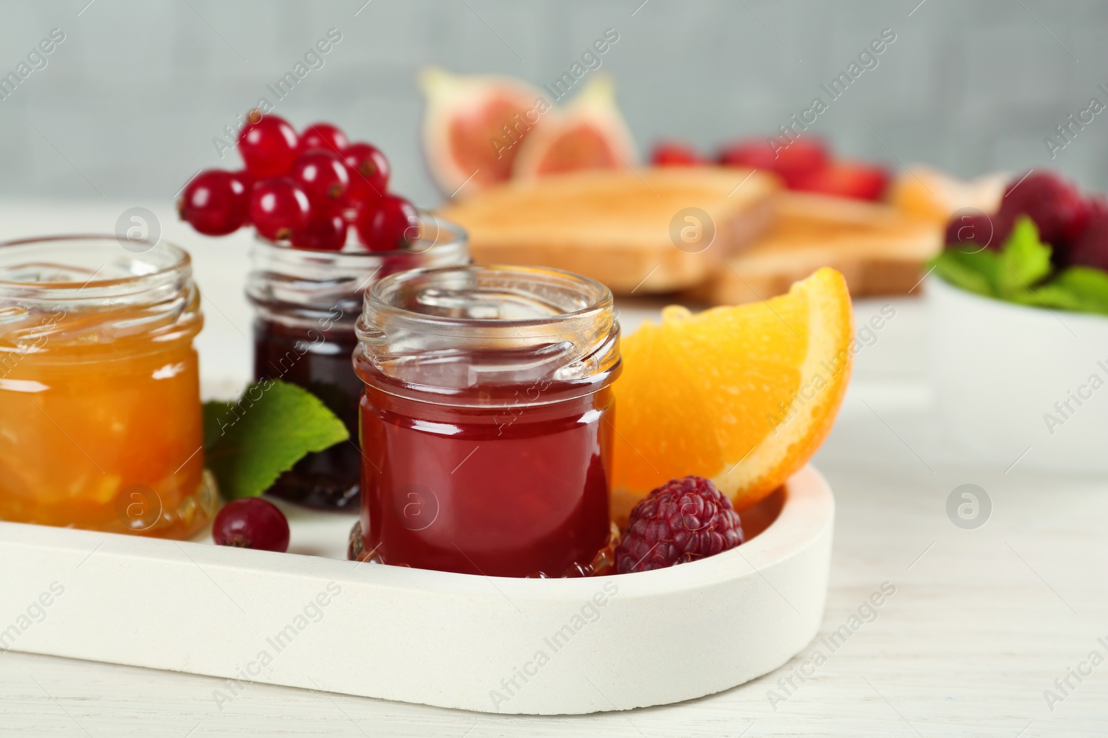 Photo of Jars with different sweet jams and ingredients on white wooden table