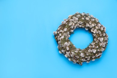 Photo of Wreath made of beautiful willow flowers on light blue background, top view. Space for text