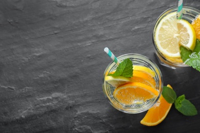 Photo of Flat lay composition of delicious orange lemonade with soda water and mint on black table, space for text. Fresh summer cocktail