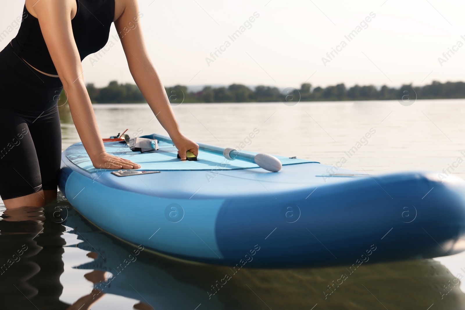 Photo of Woman standing near SUP board in water, closeup