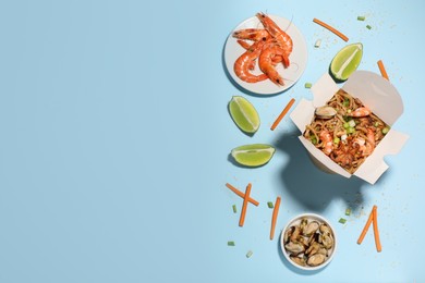 Flat lay composition with noodle wok and ingredients on light blue background. Space for text