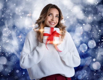 Image of Beautiful young woman with Christmas present on color background