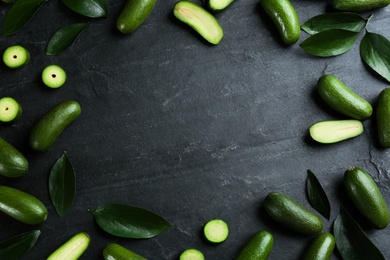 Frame made of fresh seedless avocados with green leaves on dark table, flat lay. Space for text