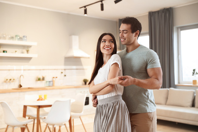 Photo of Lovely young interracial couple dancing at home. Space for text