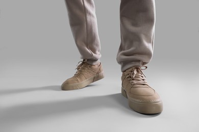 Man wearing stylish sneakers on light grey background, closeup