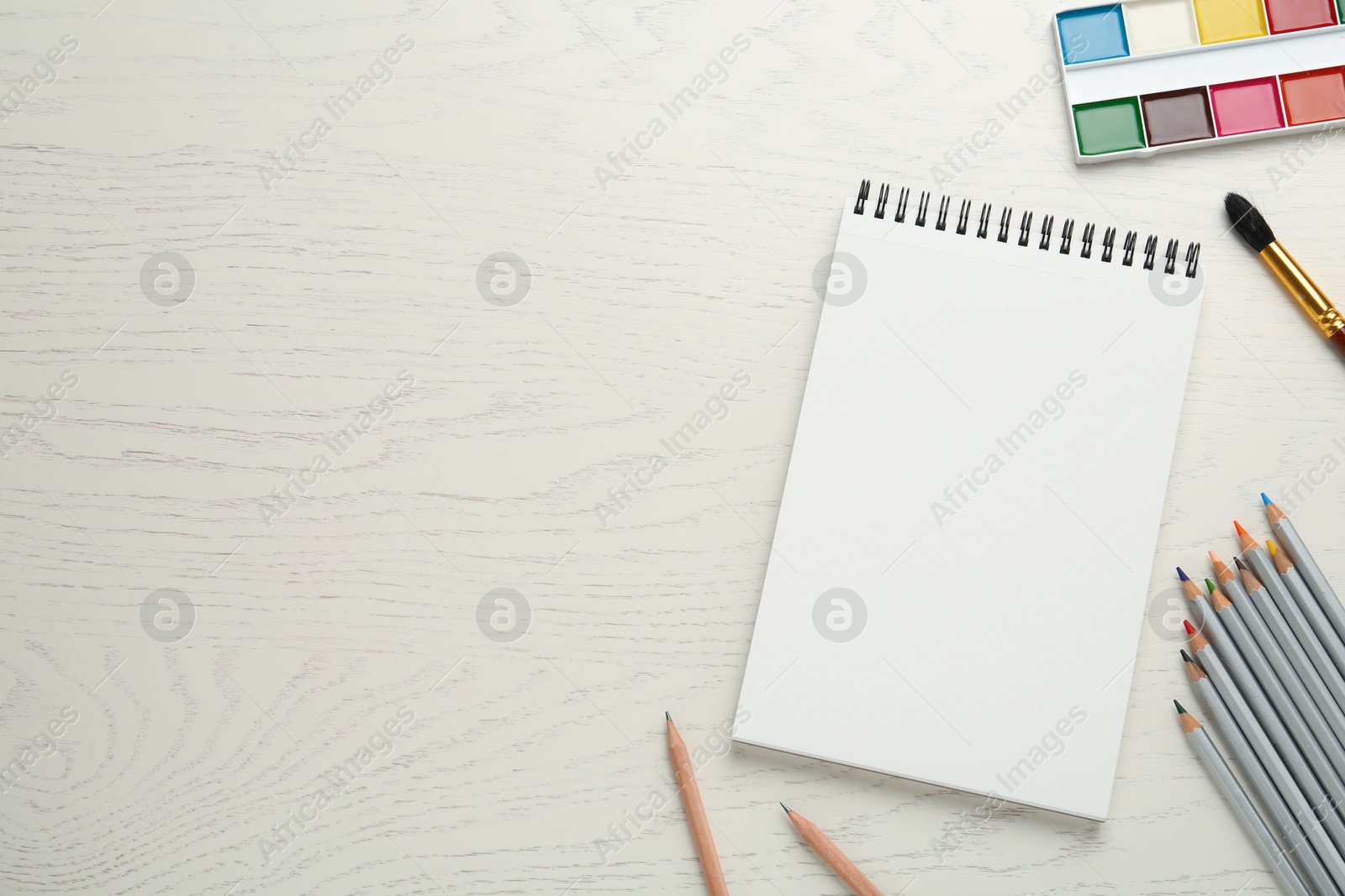 Photo of Flat lay composition with blank sketchbook on white wooden table. Space for text