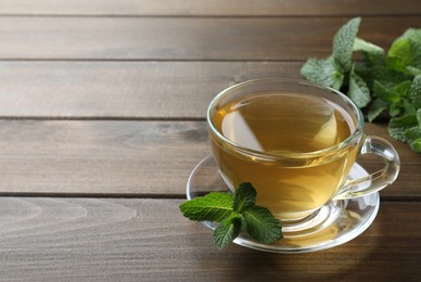 Cup of aromatic green tea with fresh mint on wooden table. Space for text