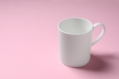 Photo of White ceramic mug on pink background. Space for text