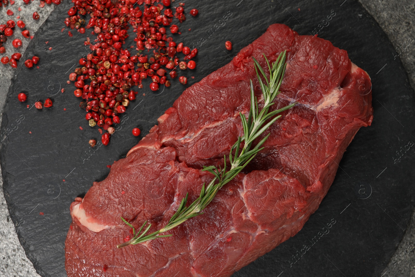 Photo of Piece of raw beef meat, rosemary and red peppercorns on table, flat lay