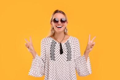 Photo of Portraitsmiling hippie woman showing peace signs on yellow background