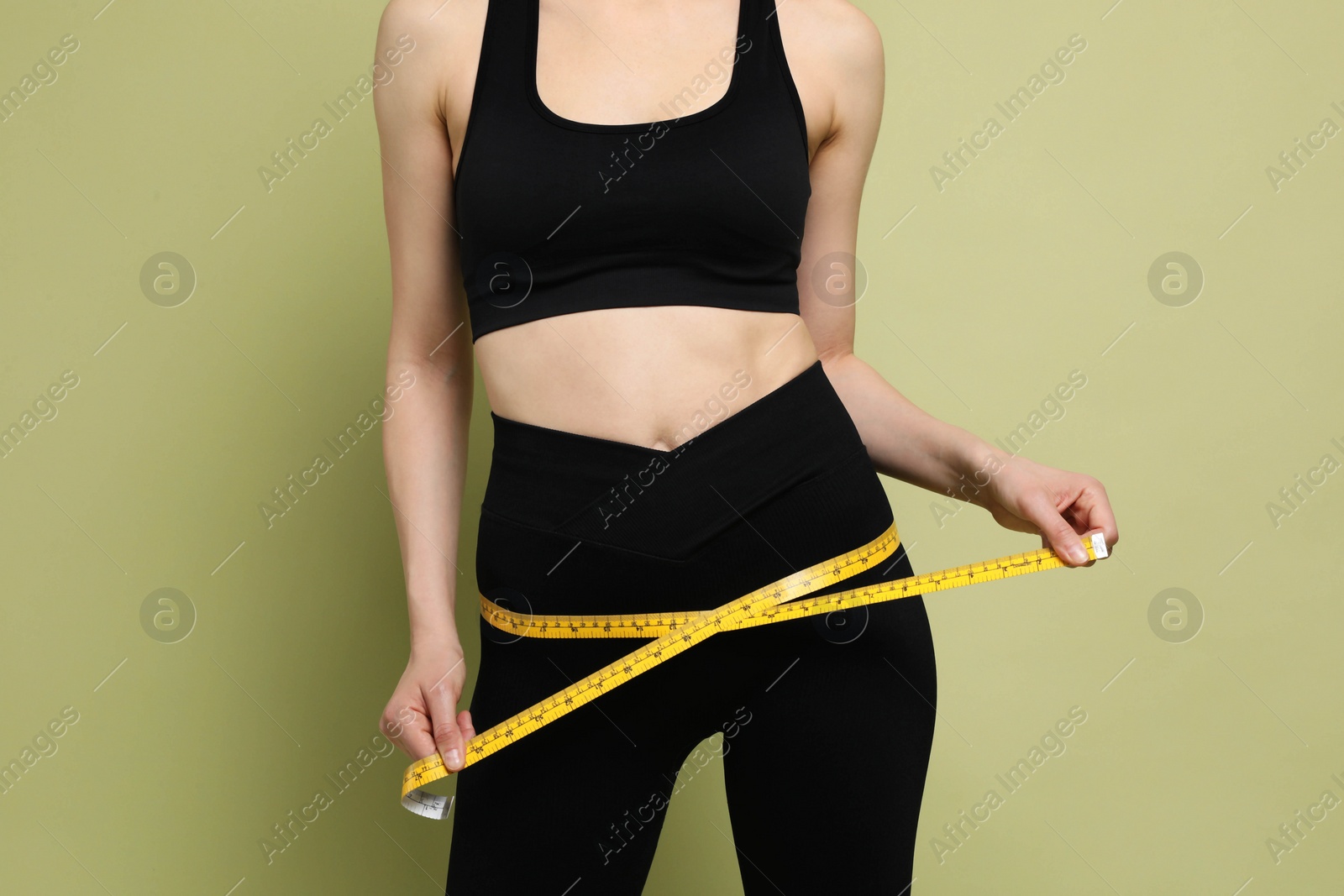 Photo of Woman with measuring tape showing her slim body on green background, closeup