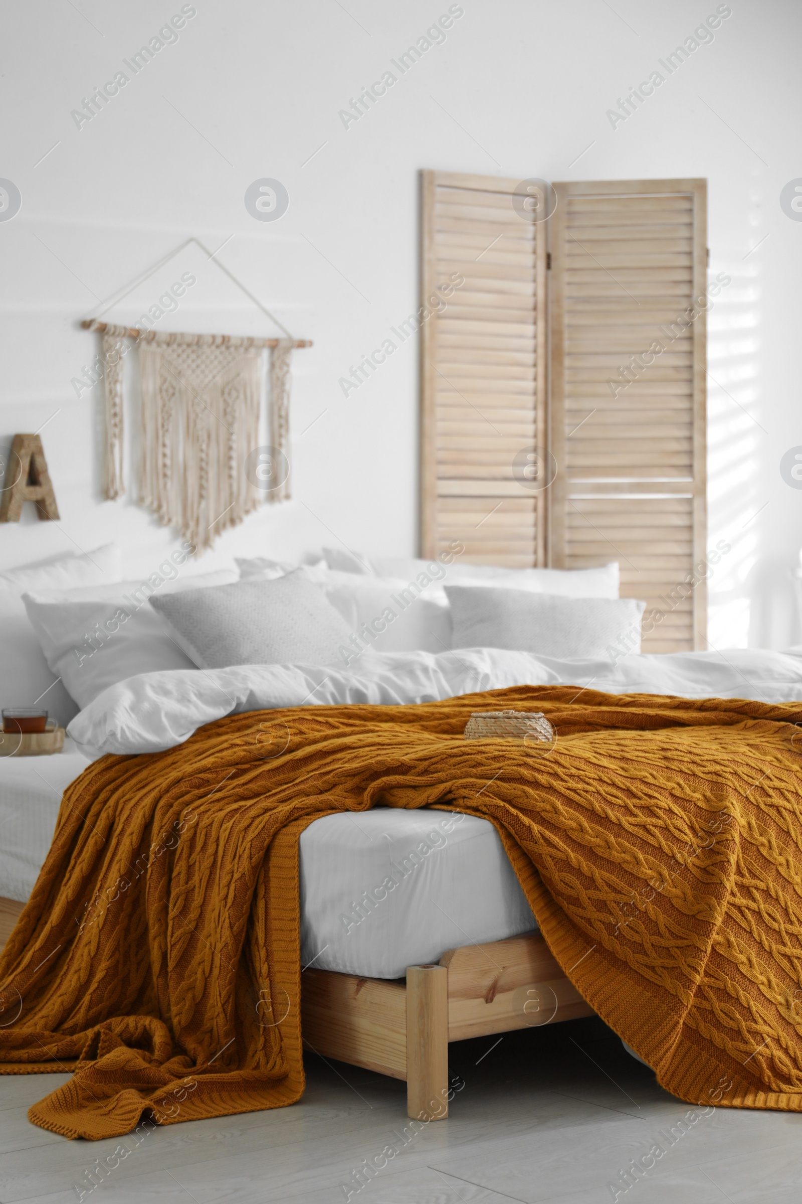 Photo of Comfortable bed with warm knitted plaid in stylish room interior