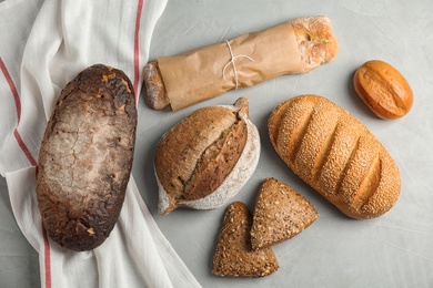 Photo of Different kinds of fresh bread on grey table, flat lay