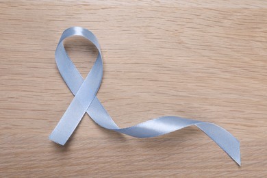 International Psoriasis Day. Ribbon as symbol of support on wooden table, top view. Space for text